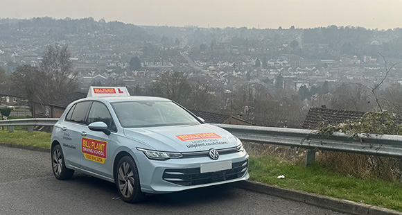 driving school car parked on a hillside with a view of the city skyline offering driving lessons for beginners 5 essential driving tips