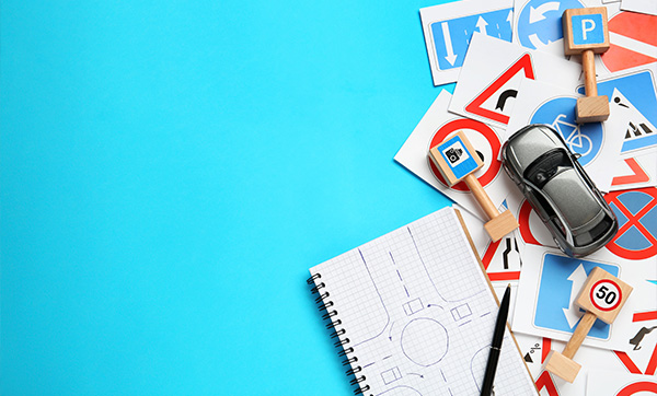toy car on a blue background surrounded by traffic signs and a notebook with road drawings ideal for learning road signs and driving skills 2