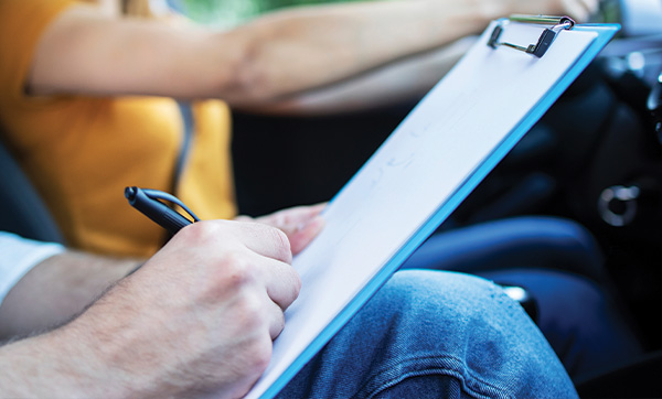 person holding clipboard while taking notes during driving lessons